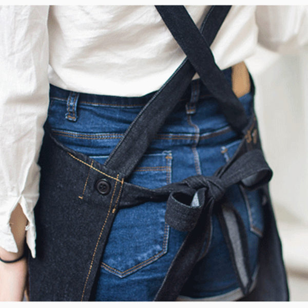 Tablier en denim noir et bleu avec des bretelles croisées dans le dos